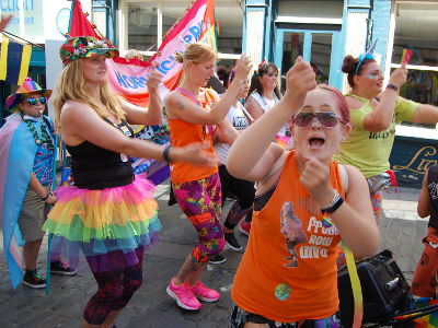 Colourful people dancing in the Norwich Pride procession.