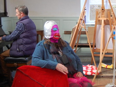 A woman wearing a mask with huge red lips posing for artists at Oulton Chapel.