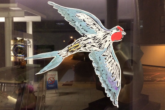 A close-up of a swallow, painted on the large West Atrium window.