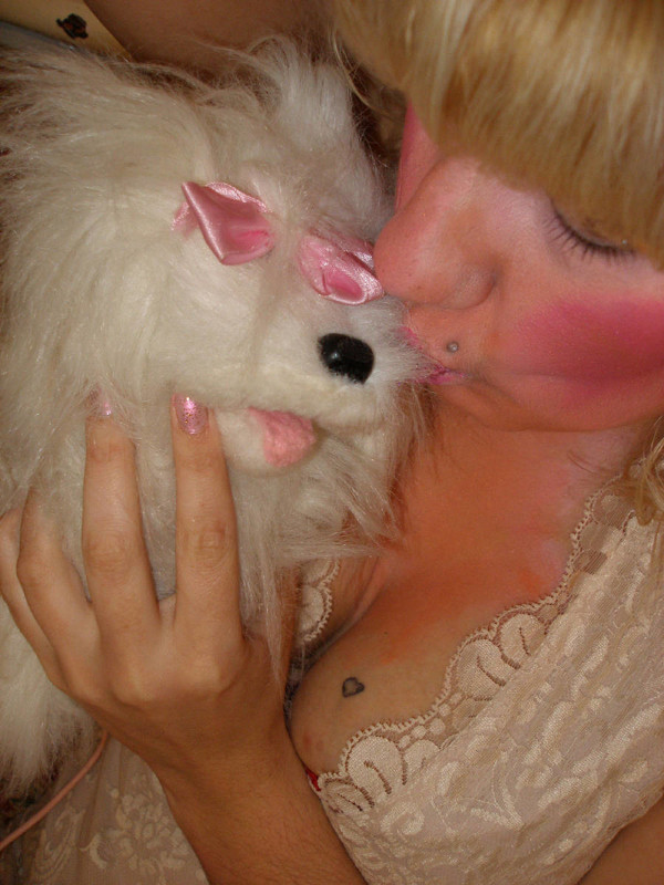 A close-up of Chrissy Sabberton kissing a white, fluffy teddy bear dog.
