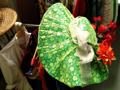 A photo of the Dandy's clothes rack, with a big green hat in the foreground.