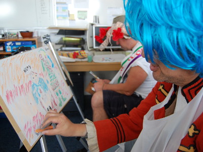A Stepping Stone artist with a blue wig painting Putinca.